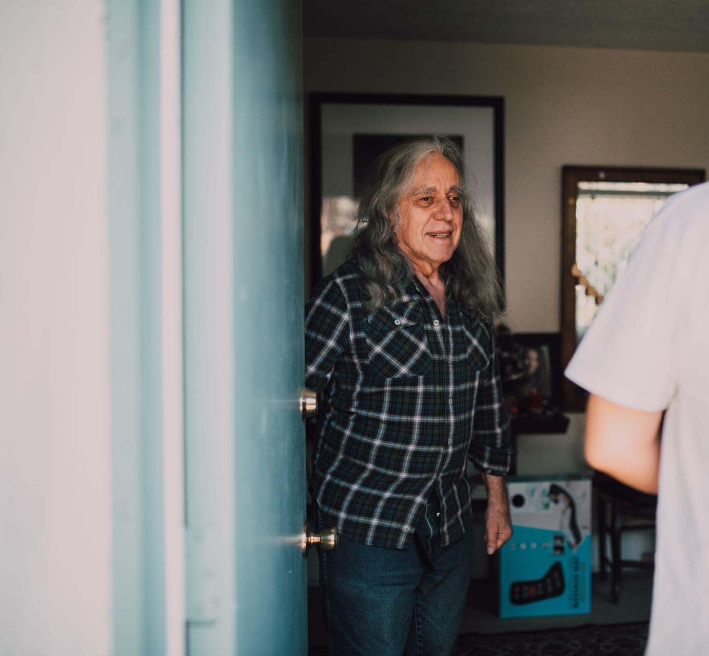 An older man warmly welcoming his carers at his front door